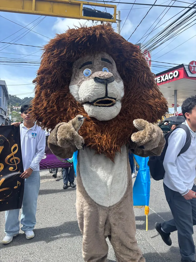 Mascota león del colegio saludando durante un desfile en la calle