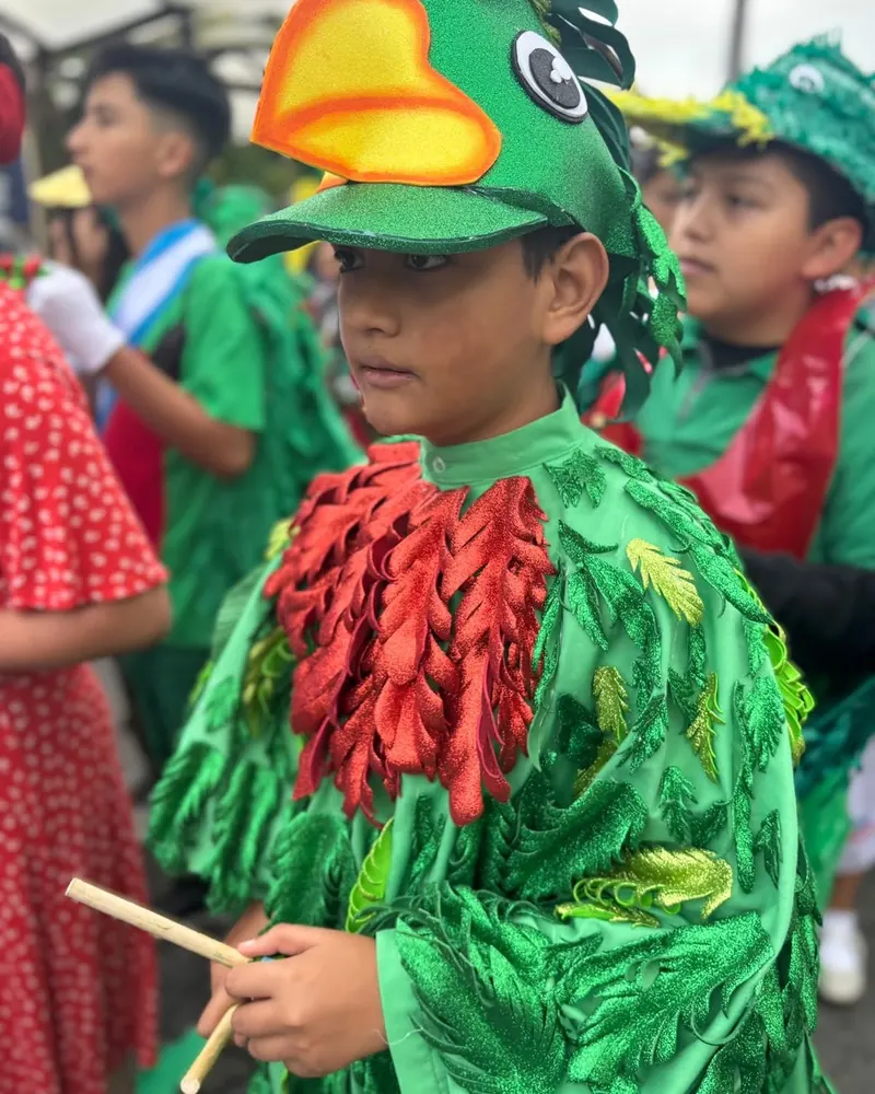 Niño disfrazado de quetzal con traje verde y rojo