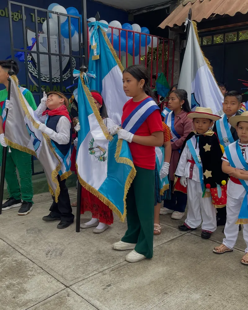 Estudiantes con banderas y bandas celestes y blancas frente a la entrada del colegio