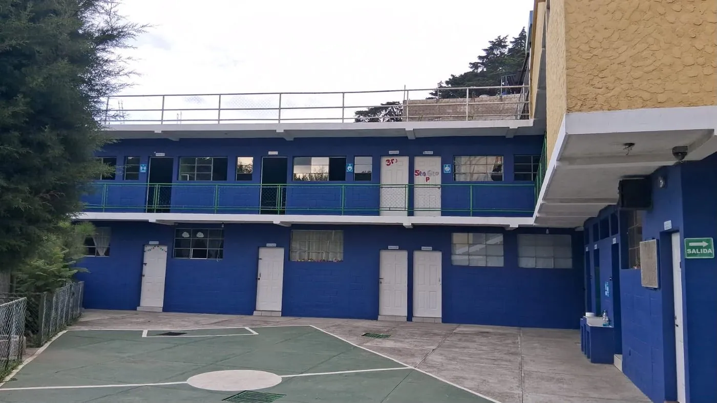 Edificio del Colegio Tecnológico SINAÍ: aulas en dos niveles pintadas de azul y patio con cancha